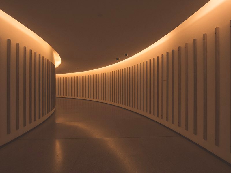 Curved corridor lit by concealed cove lighting